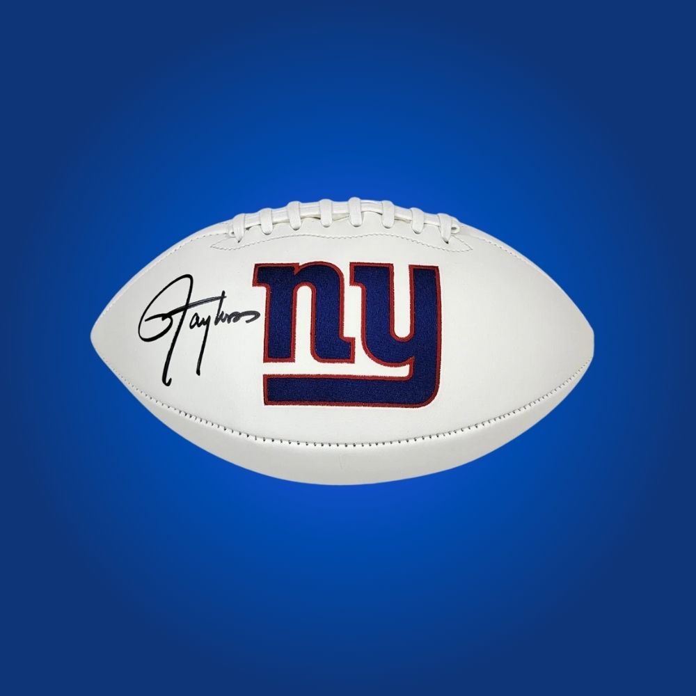 New York Giants logo football signed by Lawrence Taylor, showing player signature and team branding.