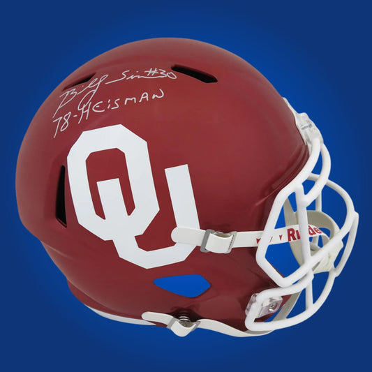 Autographed Oklahoma Sooners full size replica helmet signed by Billy Sims, displayed on a clean white background. SportsMarkets memorabilia photo.