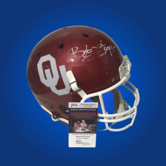 Autographed Oklahoma Sooners full size replica helmet signed by Bob Stoops, displayed on a clean white background. SportsMarkets collectible memorabilia image.